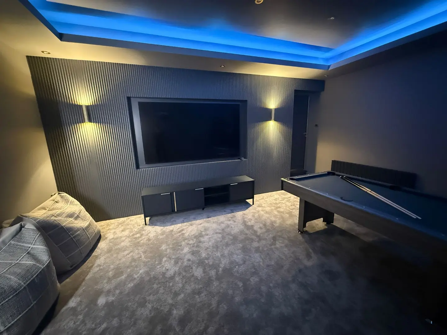 Double garage converted into a cinema room with dark slate wall panels, a blue LED ceiling and a pool table